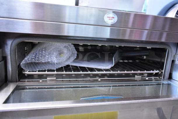 Stainless steel commercial oven with a caution label. Includes rack and trays, packaged in bubble wrap. Excellent condition.