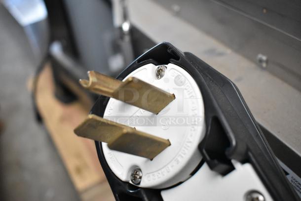 Close-up of a heavy-duty power plug showing brass prongs and a white casing labeled "50A 125/250V," indicating high capacity.