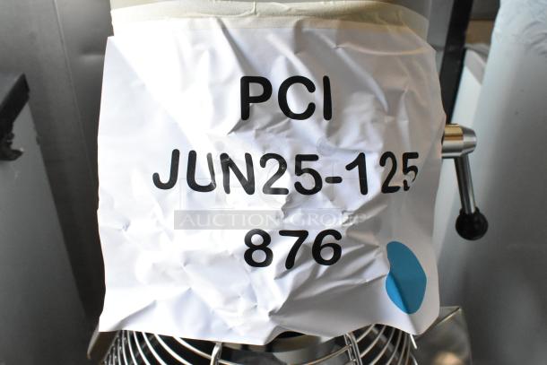 Industrial kitchen mixer with crumpled label reading "PCI JUN25-125 876," stainless steel finish, sturdy condition.