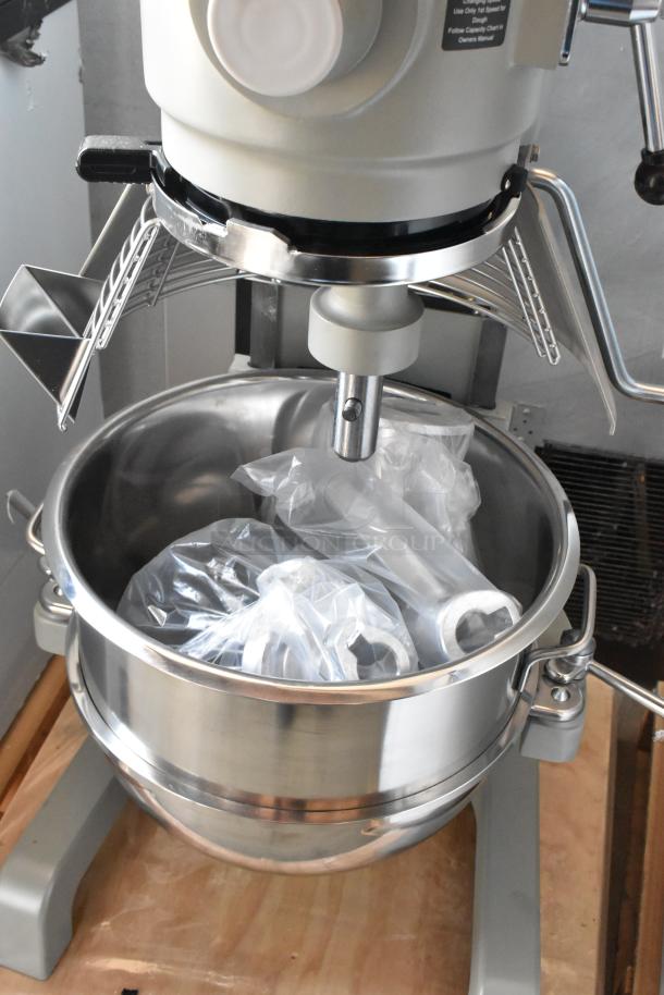 Commercial dough mixer with stainless steel bowl and attachments in plastic. Appears in excellent condition.