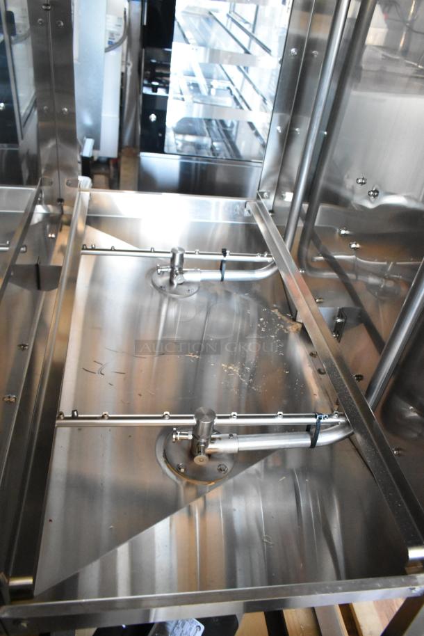 Stainless steel commercial machine interior, featuring pipes and supports, shows signs of use, ideal for industrial settings.