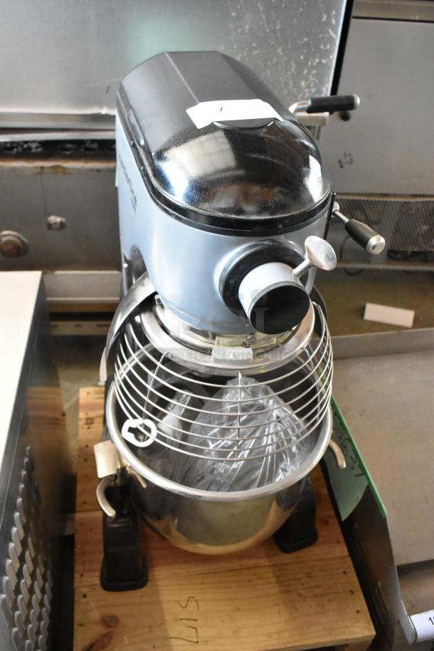 Industrial stand mixer with stainless steel bowl and safety guard, used condition. Top label shows model number, ideal for bakeries.