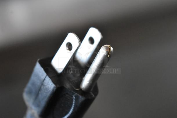 Close-up of a three-prong electrical plug in good condition, showing a black casing and metal prongs.