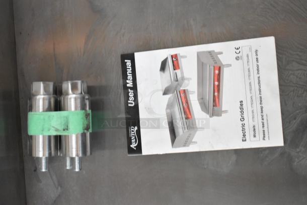 Dual metal griddle screws with green band and Avantco electric griddle user manual on metal surface, indicating compatibility.