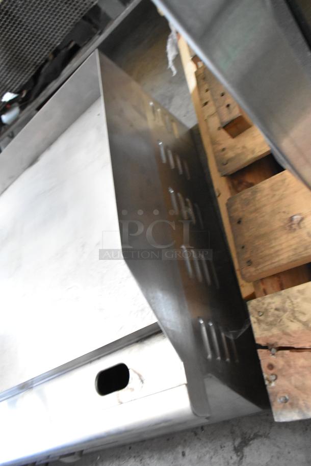 Stainless steel commercial kitchen hood, slightly used with ventilation slots. Mounted on a wooden pallet for shipping.