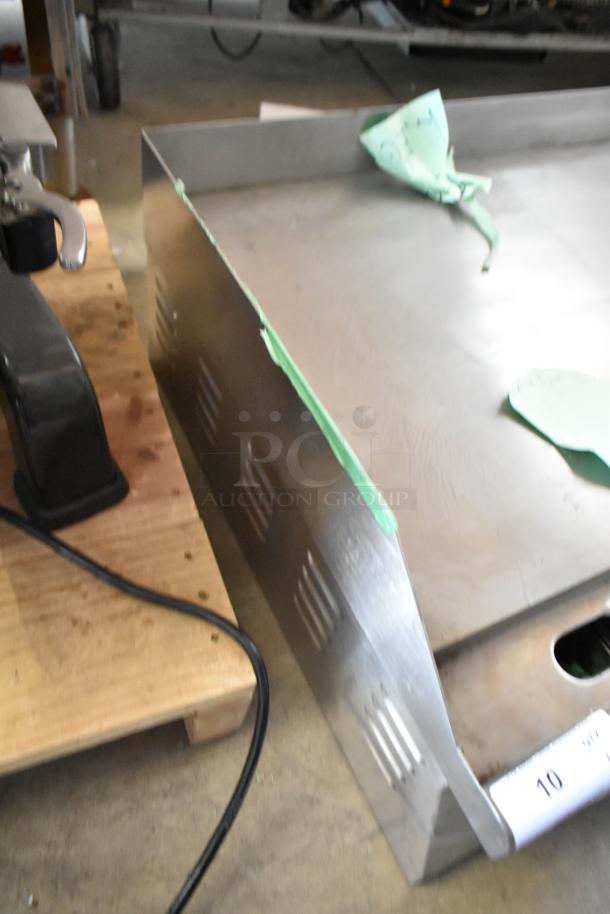 Metal vent cover with protective film, slight wear. Auction lot number visible. Ideal for industrial applications.