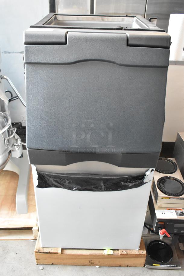 Commercial ice maker with gray plastic exterior, compact size, in good condition, on wooden pallet. No visible labels.