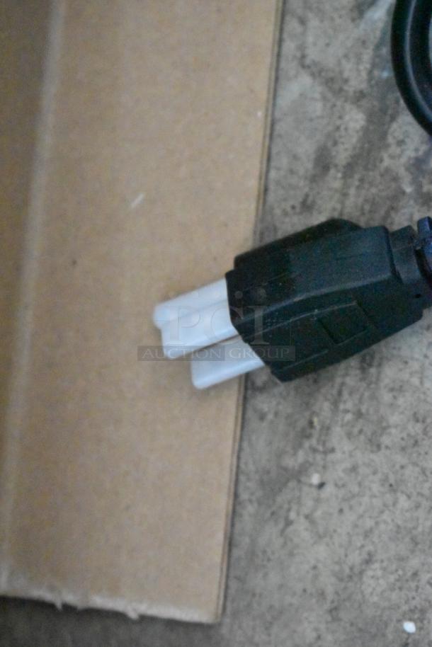 Industrial power plug, black casing with two white prongs, used condition. Ideal for heavy-duty equipment.