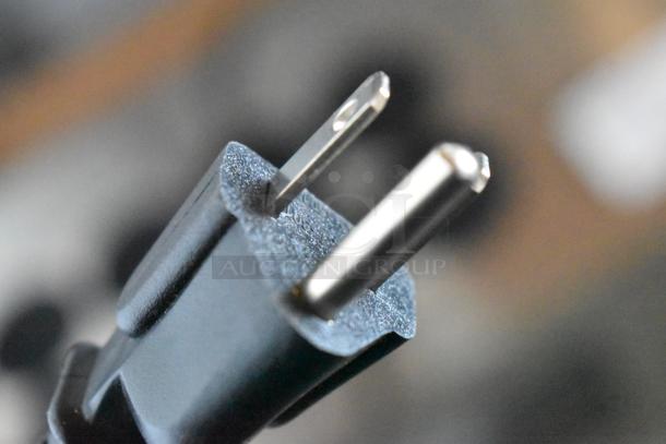 Close-up of a standard two-prong electrical plug, black casing, metal prongs, good condition, no visible markings.