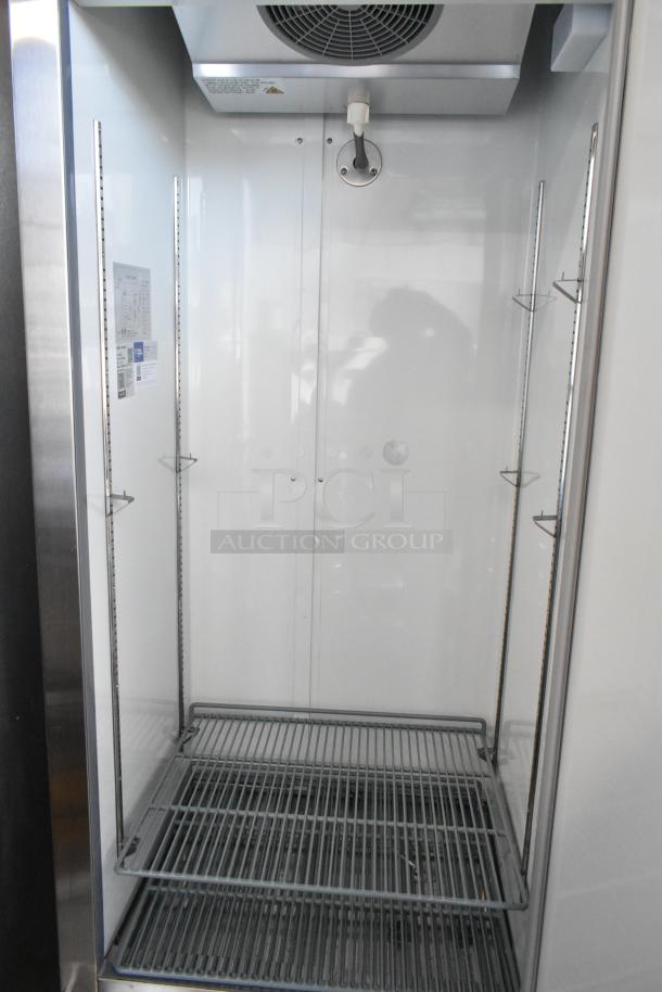 Commercial freezer unit, stainless steel interior, adjustable shelving, ceiling fan, control labels on the inner side, good condition.