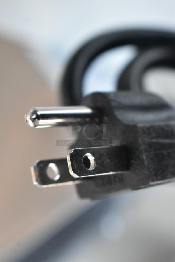 Close-up of a three-prong power plug with black casing and silver metal prongs. Appears in good condition.