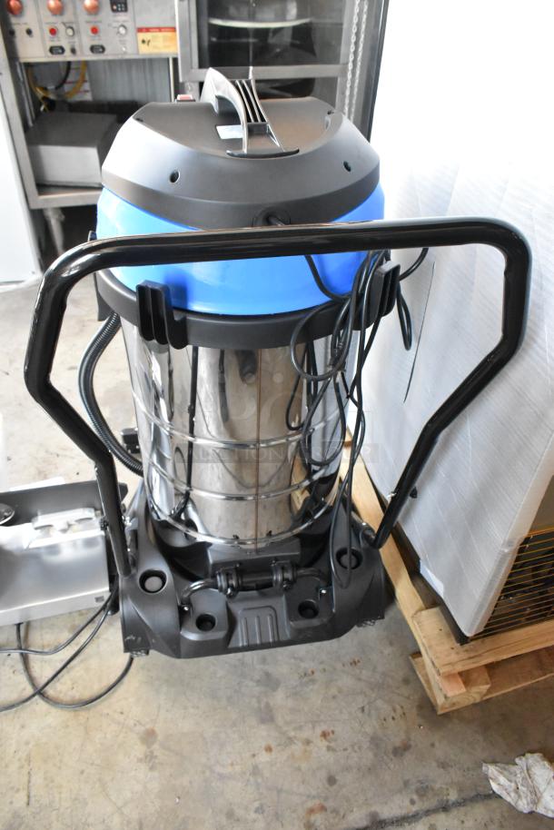 Industrial vacuum cleaner with a stainless steel body and blue top. Features durable wheels, cords, and a handle for mobility.