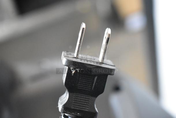 Close-up of a worn two-prong black electrical plug with visible scratches. No labels or markings shown.