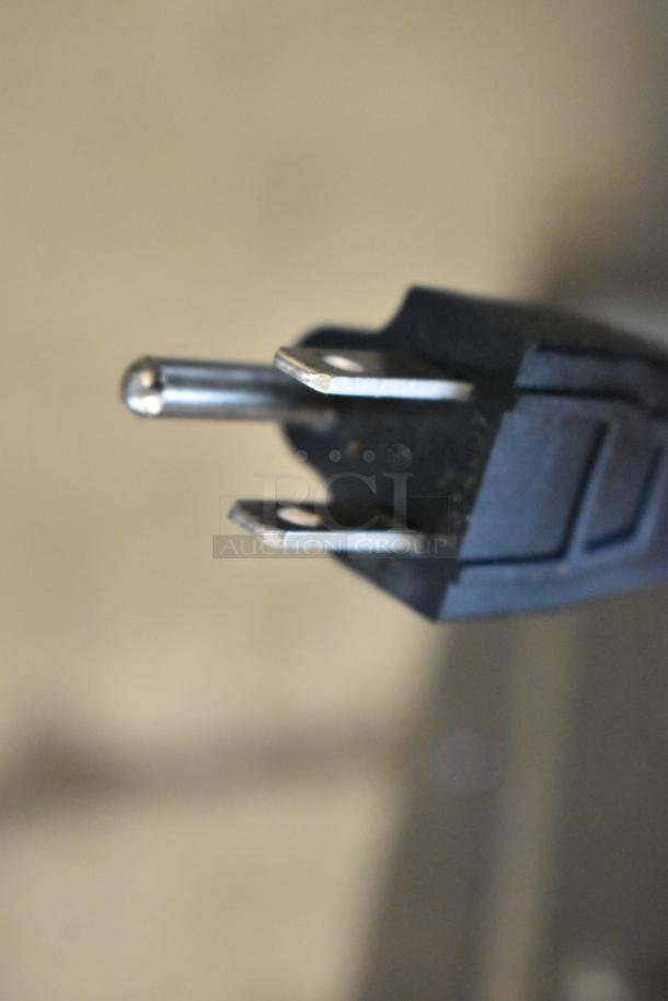 Close-up of a standard 3-prong electrical plug with black casing. Plug appears in good condition, designed for European outlets.