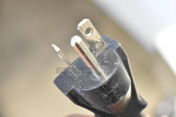 Close-up of a black three-prong electrical plug with visible "SL" and "15A" markings, in good condition.