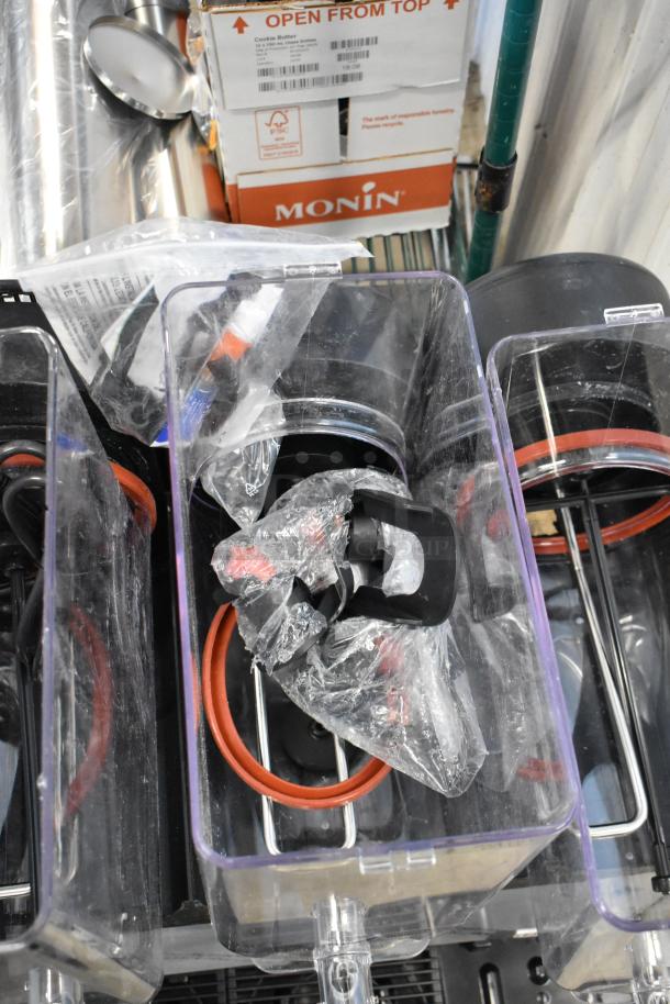 Large clear plastic containers with spigots and red gaskets, some wrapped, condition appears unused. Monin boxes nearby.