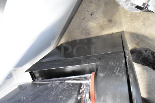 Close-up of a black appliance, possibly a refrigerator or oven, showing edges and hinges. Condition appears new. No visible markings.
