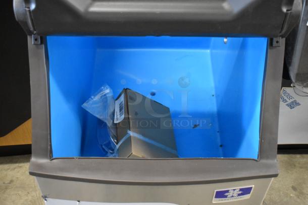 Blue bin with a brown box inside, featuring a barcode label. The bin is open, showing good condition and clean interior.