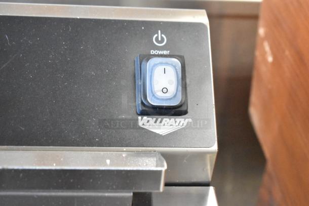 Vollrath power switch close-up on a stainless steel appliance, featuring the logo and a backlit on/off button.
