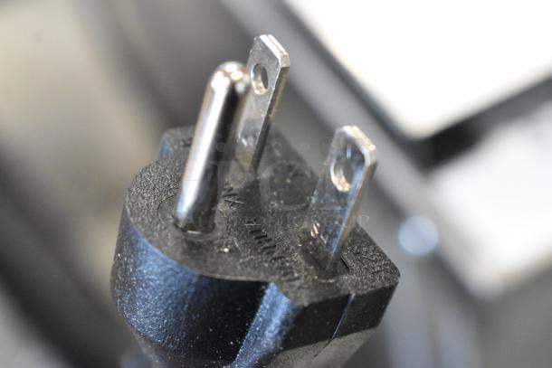 Close-up of a black three-prong electrical plug, slight wear visible. No other distinct markings or indications.