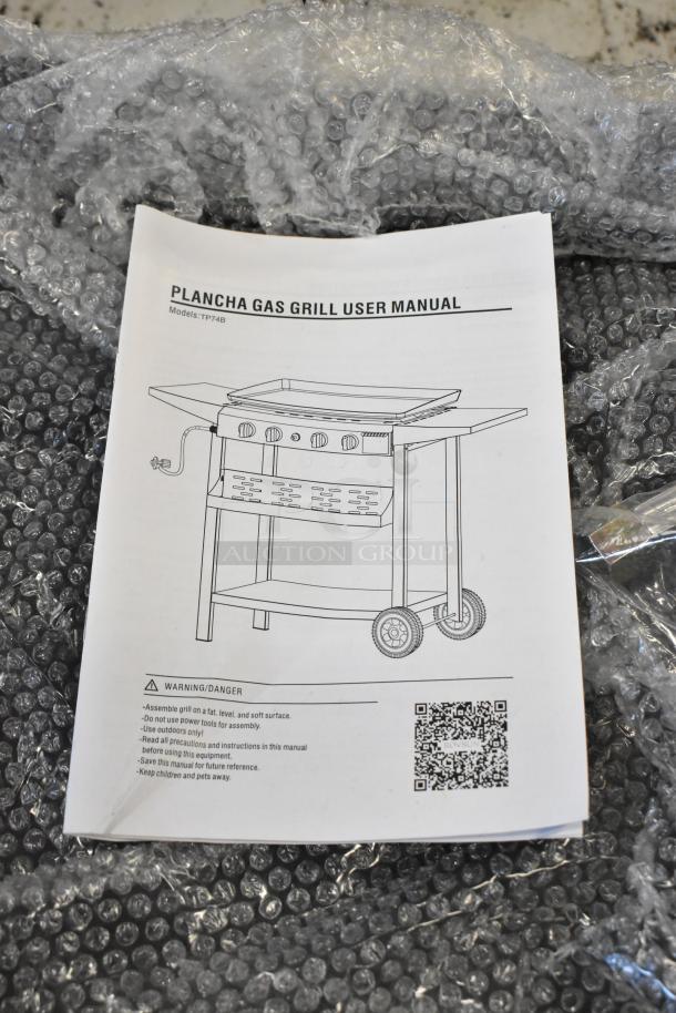 Plancha gas grill user manual cover, model TP74B, showing assembly instructions and safety warnings, on bubble wrap.