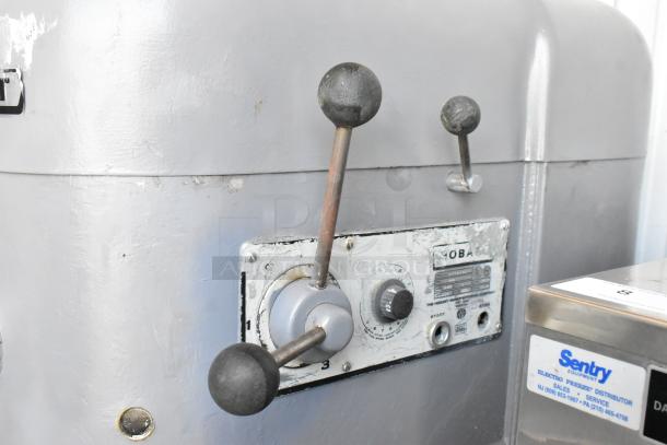 Industrial machine control panel with levers and dials, worn condition. Label reads "Hobart." Another label: "Sentry Equipment."