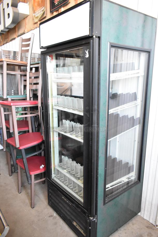 Commercial glass door refrigerator with black trim, multiple shelves, and interior lighting. Used condition, no visible tags.