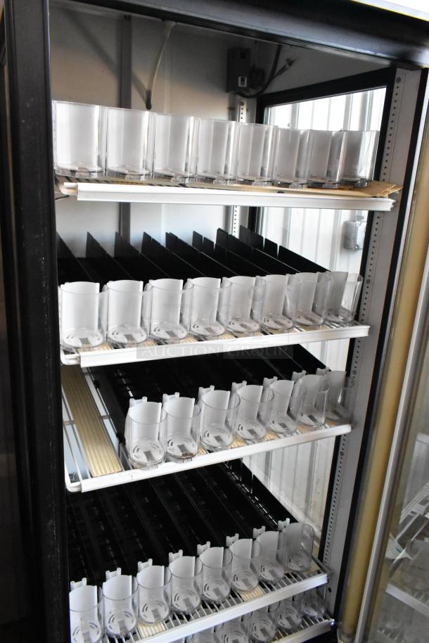 Commercial refrigerated display case with multiple shelves, each with transparent cylindrical dispensers. Pre-owned condition.