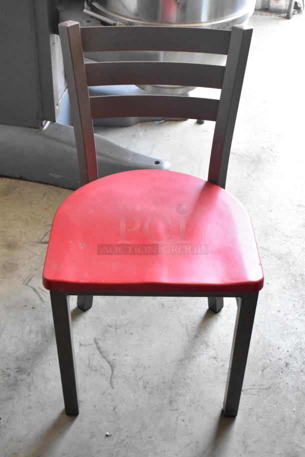 Red seat metal chair with a ladder back design, showing minor wear. Solid construction, ideal for indoor use.