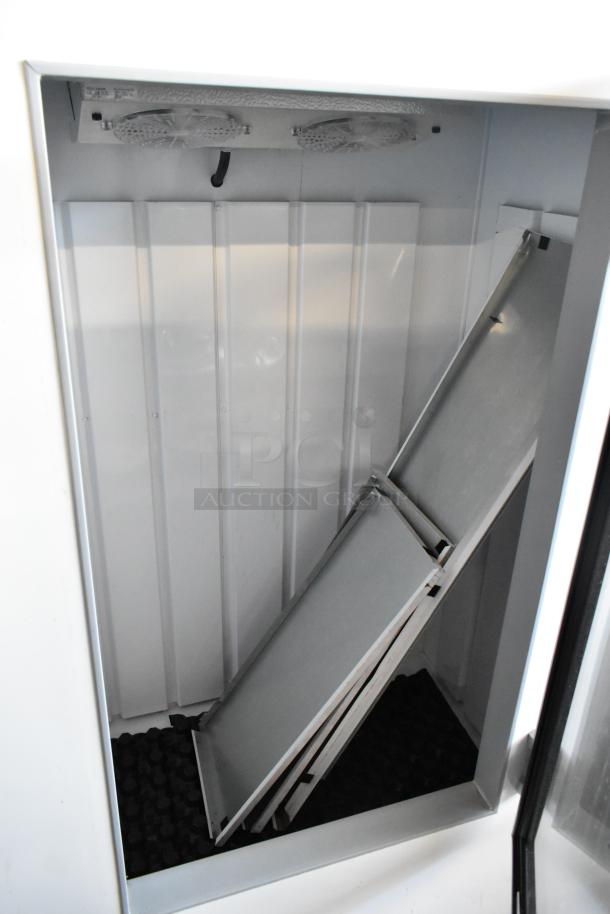 Commercial display freezer interior with shelves, cooling fans, and metal panels. Good condition, clean and spacious.