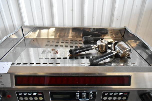 Commercial espresso machine with portafilters, stainless steel finish, visible control panel, in used condition.
