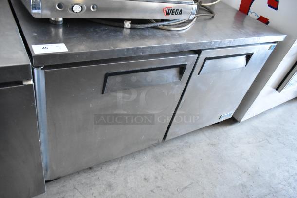 Stainless steel double-door undercounter fridge, minor surface wear, brand label "Wega," auction tag with number 46.