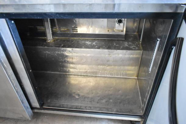Industrial stainless steel refrigerator interior, visible wear, temperature control panel, open door, no shelves.