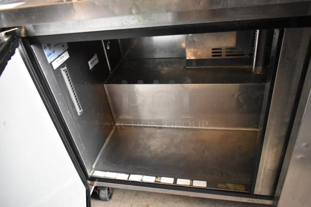Stainless steel commercial refrigerator interior, open door, with adjustable shelving and labels. Good condition.
