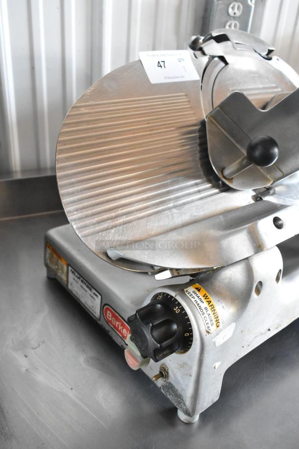 Berkel meat slicer with adjustable thickness knob, model number visible, in good condition with minor wear, includes safety warning label.