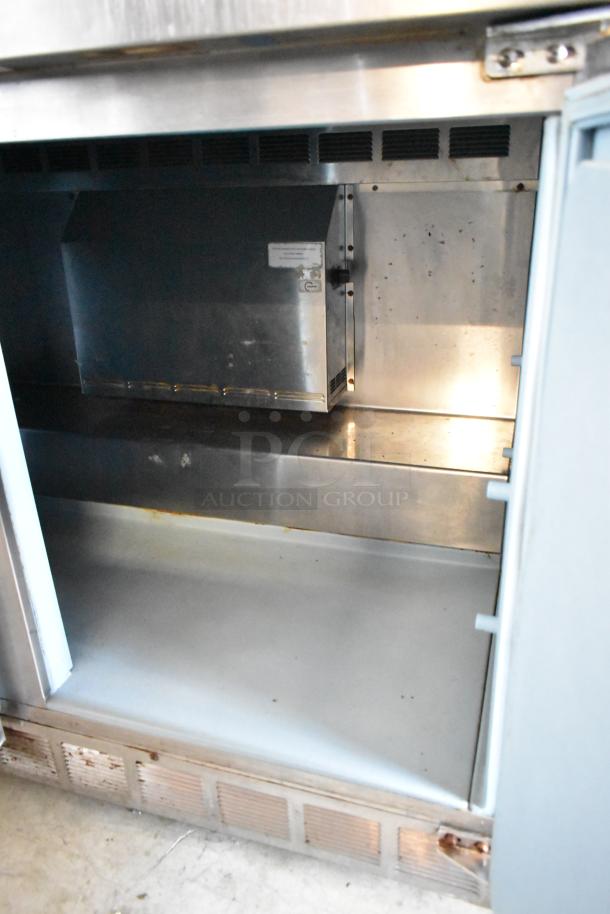 Commercial refrigerator interior, stainless steel, used condition, visible wear. Vent and interior compartment.