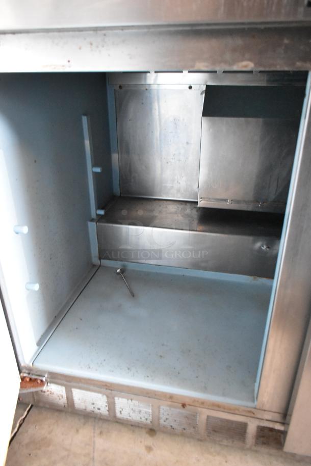 Stainless steel commercial oven interior with minor wear, showing shelves and vent. Includes small thermometer on the bottom.
