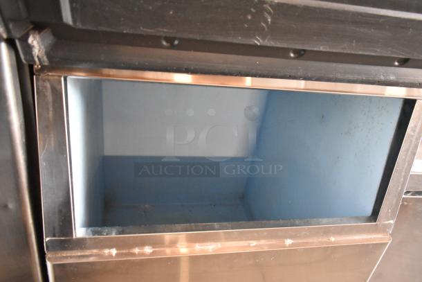 Commercial ice machine interior, stainless steel frame, shows moderate wear. No visible labels or markings.