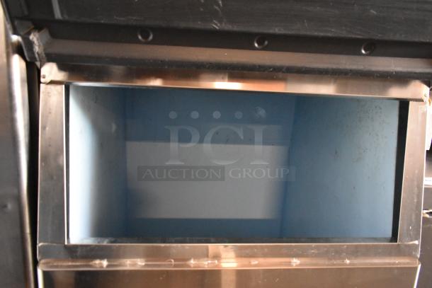 Commercial ice cooler with stainless steel frame, open lid, and blue interior. Signs of wear inside, suitable for restaurants.