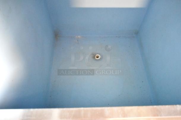 Blue industrial sink with visible drain, mild wear marks, stainless steel rim, interior depth suitable for heavy-duty use.