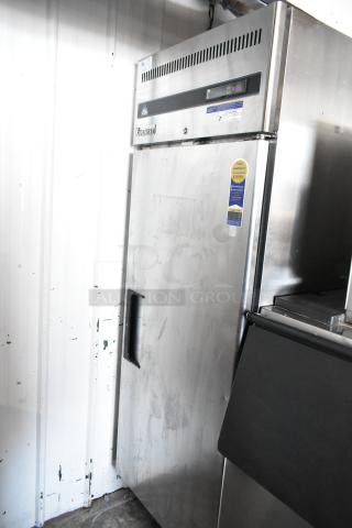 Commercial stainless steel freezer by Everest, single door, digital display, visible wear, warranty sticker on door.