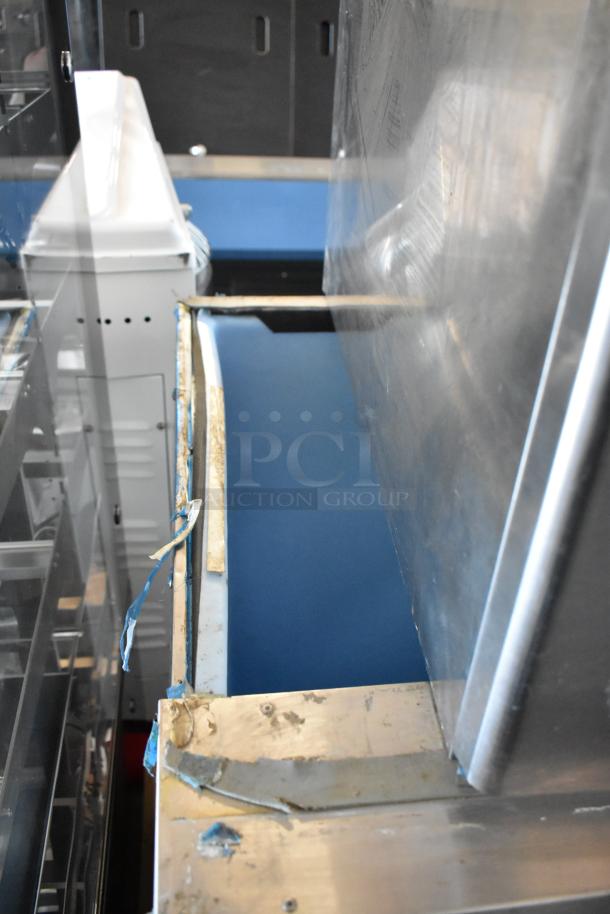 Industrial conveyor system with blue belt and metal frame, showing signs of wear and tape residue, indicating used condition.