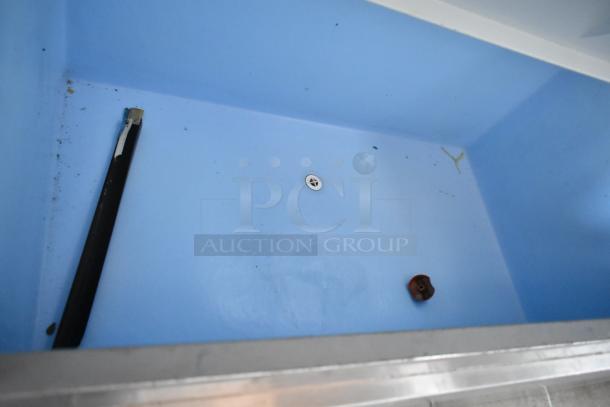 Blue plastic container with drainage hole, light wear and debris, includes attached black rod.