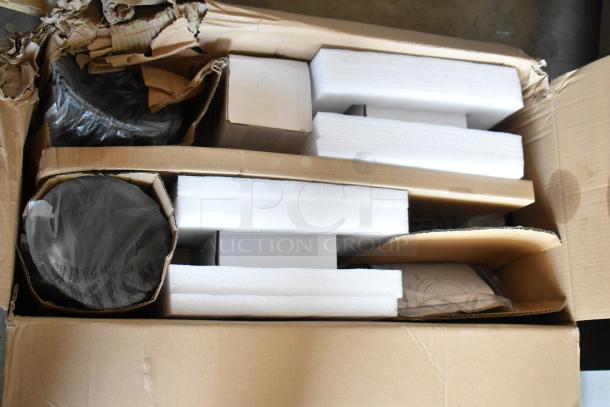 Box with foam-packed items, partially visible wrapped components, and some wear on cardboard. No labels or markings discernible.