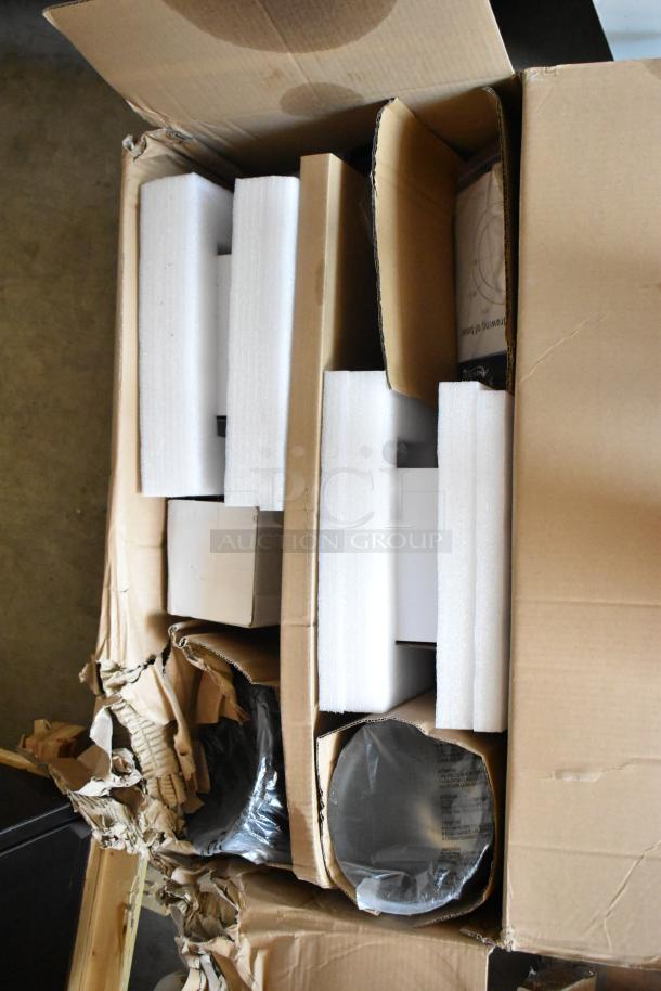 Cardboard box containing items with protective foam inserts, visible damage on box edges, contents partially obscured.