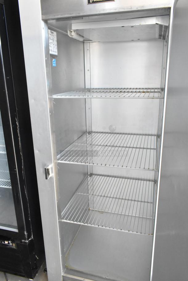 Stainless steel commercial refrigerator with four wire shelves, model label visible, in good condition.