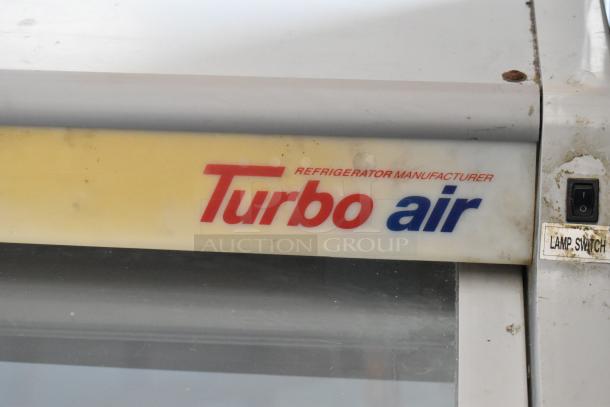 Turbo Air refrigerator with logo and lamp switch, showing signs of wear. “Refrigerator Manufacturer” text visible.