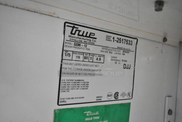 True Manufacturing label, model GDM-12, 1/5 HP, 115 V, 60 Hz, refrigerant R134A, NSF listed for packaged products.
