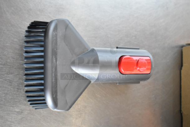 Vacuum brush attachment, gray with red release button, in excellent condition. Suitable for efficient cleaning tasks.