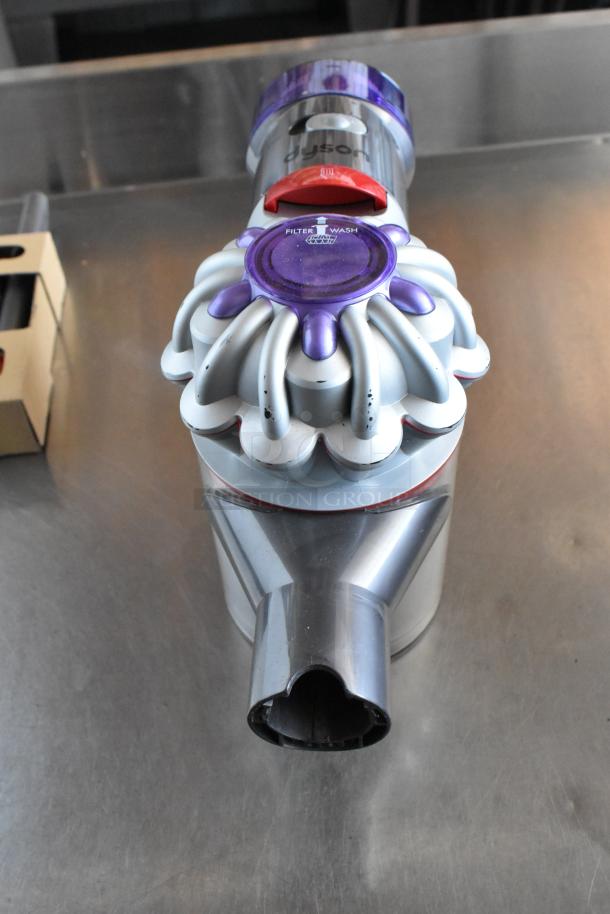 Dyson vacuum cleaner head with purple and silver design. Visible "Filter Wash" label. Good condition.